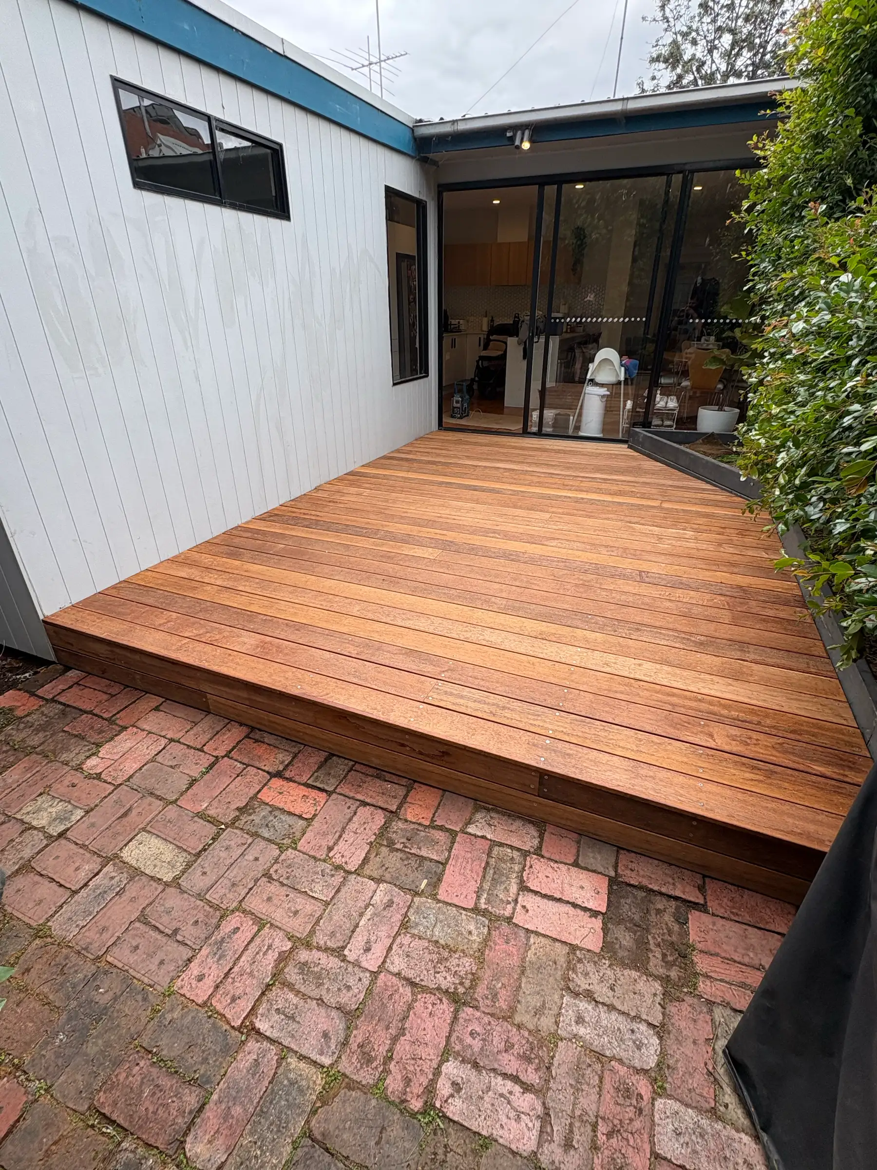 Timber deck beside brick paving and dark cladding