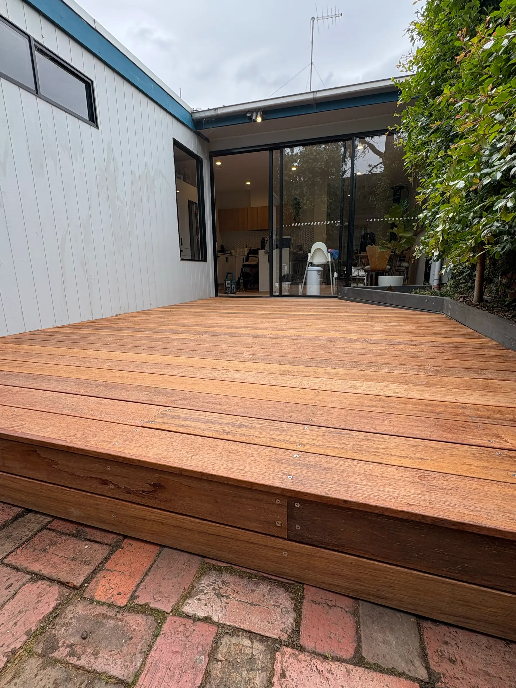 Curved timber deck edge against brick paving